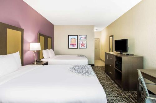 a hotel room with two beds and a flat screen tv at La Quinta by Wyndham Hillsboro in Hillsboro