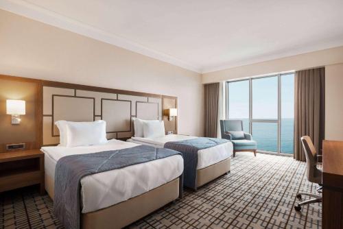 a hotel room with two beds and a chair at Ramada Plaza by Wyndham Rize in Rize