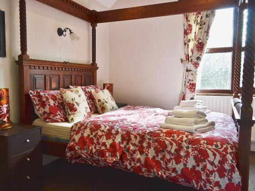 a bedroom with a bed with a red comforter and a window at Bridge House in Church Gresley