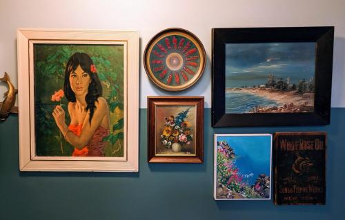 a wall with paintings and clocks on it at Jamaica Mid-Century in Seaton