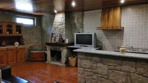 a living room with a stone fireplace and a tv at Casa Cosme in Braga