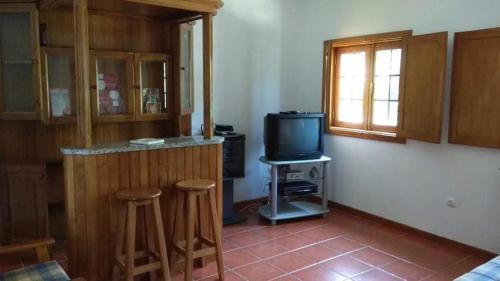 - un salon avec une télévision et deux tabourets de bar dans l'établissement Casa Cosme, à Braga