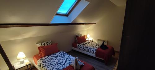 a attic bedroom with two beds and a window at Au pied du château 2 in Bellegarde-du-Loiret