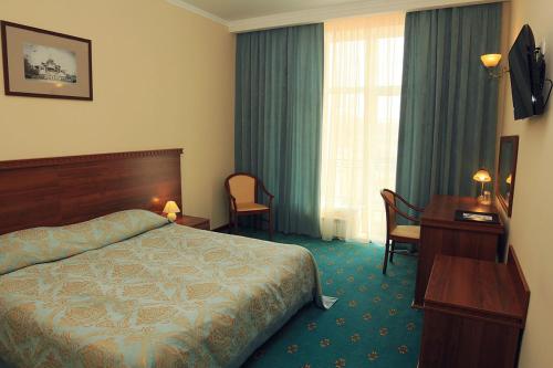 ナロ・フォミンスクにあるKupets Hotelのベッドとデスクが備わるホテルルームです。