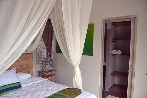 a bedroom with a canopy bed and a window at Ratna Villa in Ubud