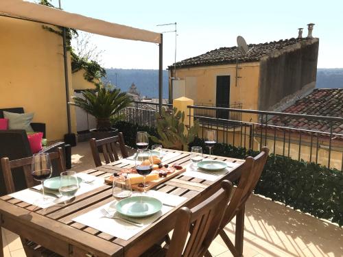 a wooden table with plates and wine glasses on a balcony at Casa Alva in Ragusa