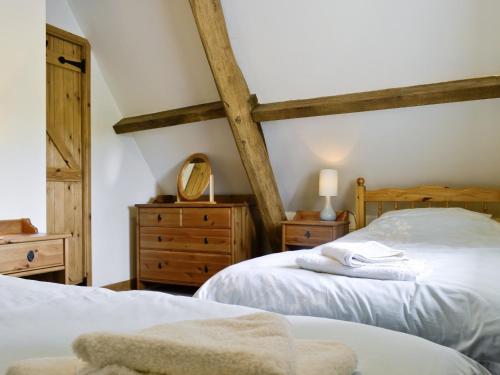 two beds in a bedroom with wooden beams at The Old Stables in Sherston