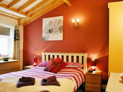 een slaapkamer met rode muren en een bed met handdoeken erop bij Wold View in Gristhorpe