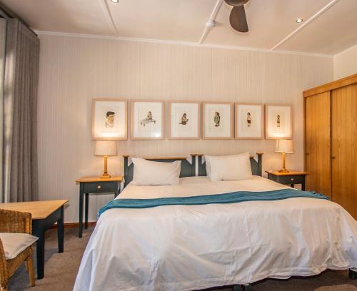 a bedroom with a large bed with three pictures on the wall at Graskop Hotel in Graskop