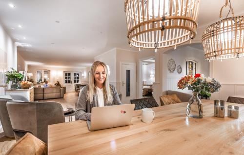 a woman sitting at a table with a laptop at Aparthotel Friesenhof in Wenningstedt