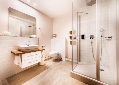 a bathroom with a shower and a sink and a toilet at Aparthotel Friesenhof in Wenningstedt