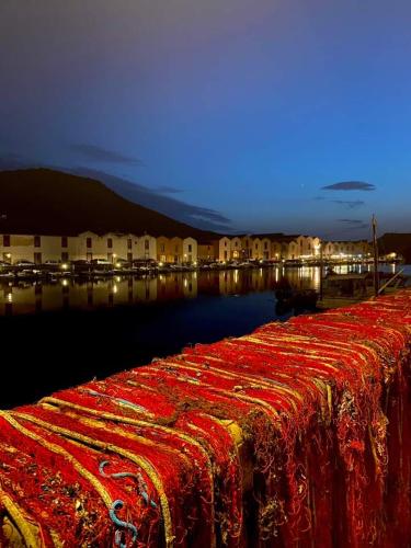 a table with a red and gold table cloth next to the water at Le Camelie camera in Bosa