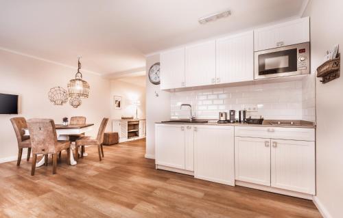 a kitchen with white cabinets and a table with chairs at Aparthotel Friesenhof in Wenningstedt