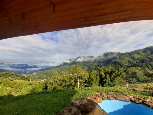 a view of the mountains from a house window at Cabana do Camelo in São Bento do Sapucaí