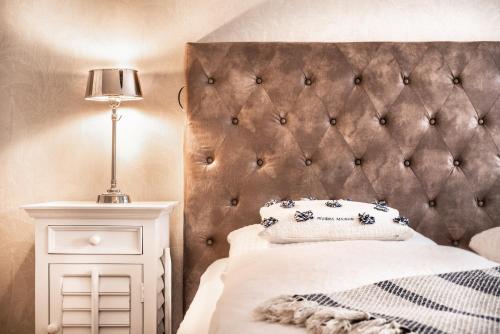 a bedroom with a padded headboard and a bed with a lamp at Aparthotel Friesenhof in Wenningstedt