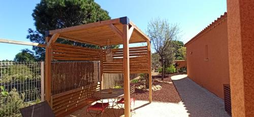 a wooden pergola in a garden next to a building at Villa SOREDE in Sorède