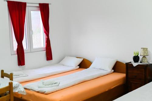 two beds in a room with red curtains at Tri bagrema KM in Mokra Gora