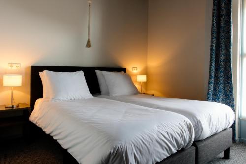 1 dormitorio con 1 cama grande con sábanas y almohadas blancas en Logementen Dokkum en Dokkum