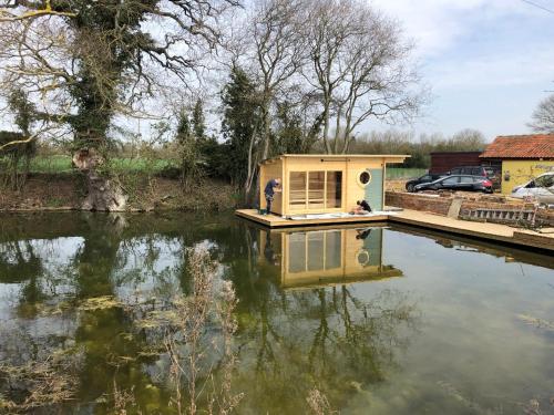 a small house sitting on top of a body of water at Cherry Trees in Stowmarket