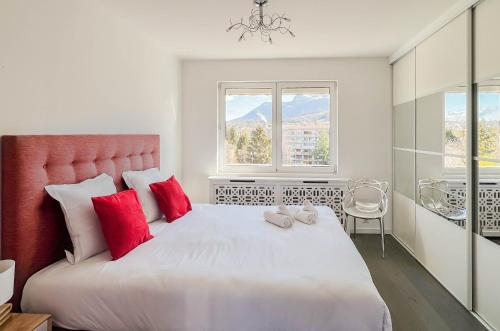 um quarto com uma grande cama branca com almofadas vermelhas em Penthouse vue incroyable lac et montagnes em Annecy