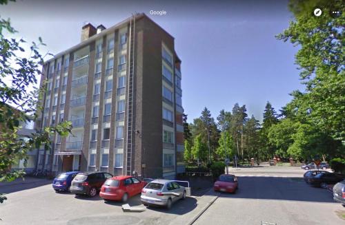 a large building with cars parked in a parking lot at Ylimmän kerroksen yksiö lähellä matkakeskusta in Lappeenranta