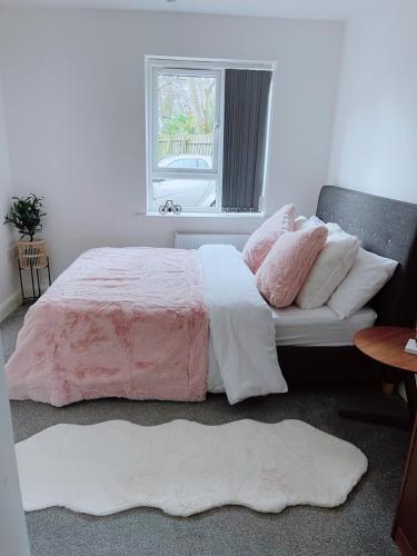 Schlafzimmer mit einem Bett mit rosa und weißer Bettwäsche und einem Fenster in der Unterkunft Shared Modern Apartment Double Bedroom With Attached Bath in Manchester