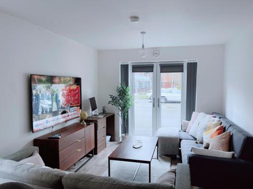 ein Wohnzimmer mit einem Sofa und einem Flachbild-TV in der Unterkunft Shared Modern Apartment Double Bedroom With Attached Bath in Manchester