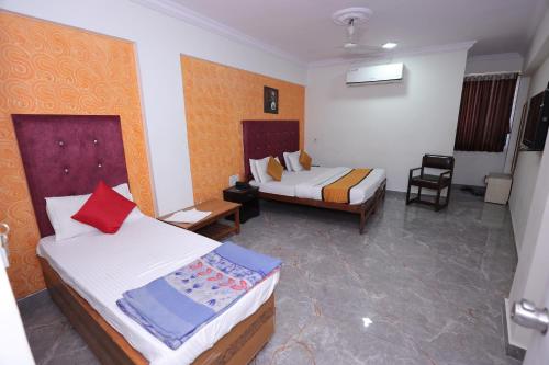a hotel room with two beds and a chair at HOTEL RUNWAY INN in Ahmedabad