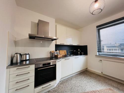 a kitchen with white cabinets and a black stove top oven at BIG-6-Guests-Kingsize-Netflix-Badewanne-Hauptbahnhof-Zentral in Koblenz