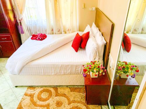 a bedroom with a bed with white sheets and red pillows at Spring Hills Hotel - Morogoro in Morogoro