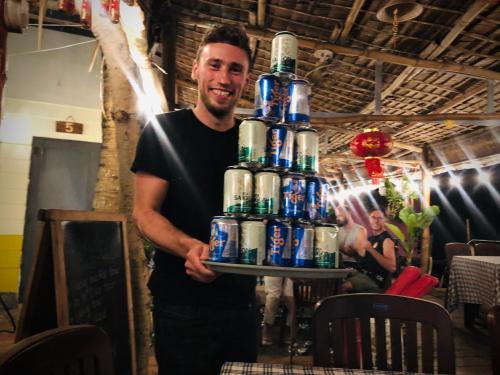a man holding a tray of cans of beer at Song Ngư Riverside Homestay in Can Tho