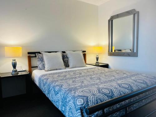 a bedroom with a bed with two lamps and a mirror at Cooks Endeavour Motor Inn in Tweed Heads
