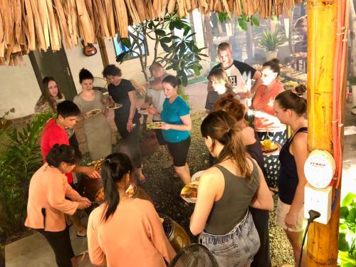 a group of people standing around in a room with food at Song Ngư Riverside Homestay in Can Tho