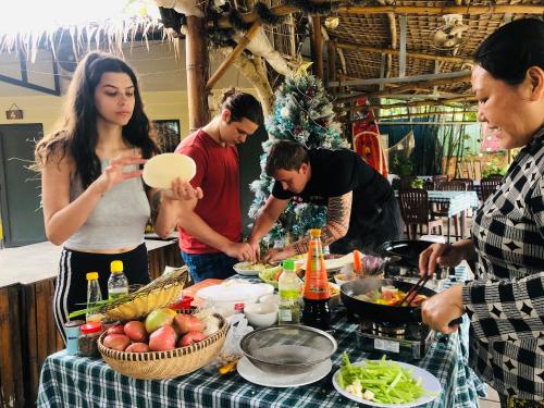 a group of people standing around a table with food at Song Ngư Riverside Homestay in Can Tho