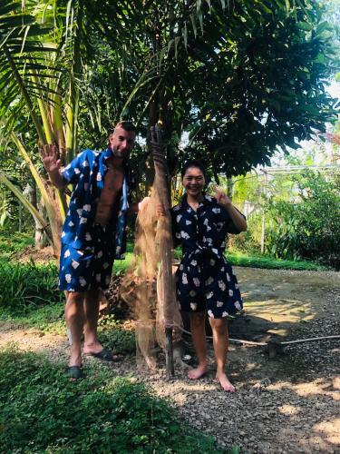 a man and a woman standing next to a tree at Song Ngư Riverside Homestay in Can Tho
