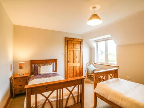 um quarto com uma cama, uma secretária e uma janela em Kiltymon Cottage em Ahakista
