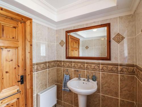 uma casa de banho com um lavatório e um espelho em Kiltymon Cottage em Ahakista