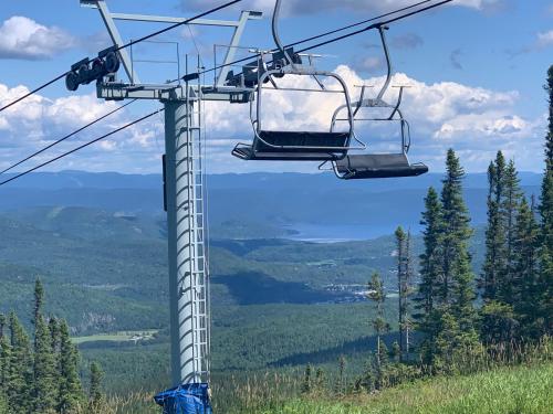 a ski lift with two chairs on a mountain at Appartement Mont Édouard, Hébergement paisible à la montagne in LʼAnse-Saint-Jean