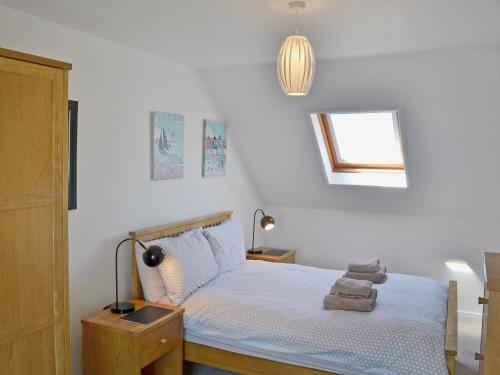 a bedroom with a bed with white sheets and a window at Dormouse Cottage in Sea Palling