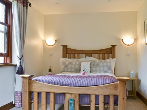 a bedroom with a wooden bed with two lights at Old Stones in Glendevon