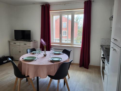 uma mesa de jantar com cadeiras e uma grande janela em appartement 40 m² proche rempart em Langres