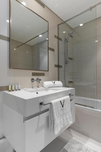 a white bathroom with a sink and a shower at Sea View with Private Beach Access! 3BR & Maid Rm in Dubai