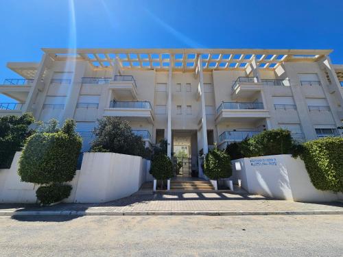a large white building with bushes in front of it at Un appartement de charme à Hammamet in Hammamet