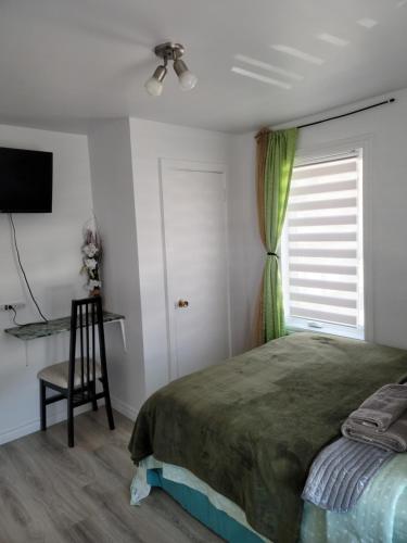 1 dormitorio con cama, ventana y silla en Downtown apartment next to highway netflix+wifi en Edmundston