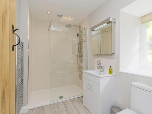a white bathroom with a shower and a sink at The Barn At Grislow Field in Baslow
