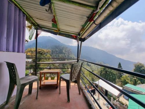 a balcony with chairs and a table and a view at Lava swagat homestay in Lava