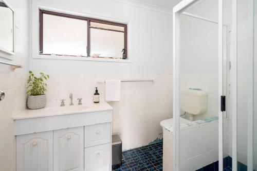 a white bathroom with a sink and a toilet at Oceanfront Sandy Beach Couples Getaway in Emerald Beach