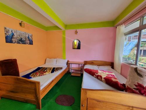 two beds in a room with green and orange walls at Lava swagat homestay in Lava