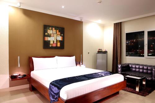 a bedroom with a large bed and a couch at Queens Hotel Angeles City in Angeles