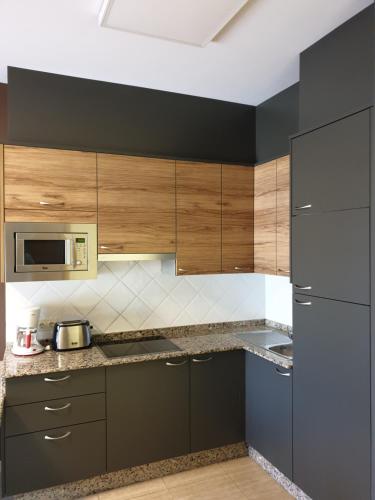 a kitchen with wooden cabinets and a stainless steel refrigerator at Apartamentos Atlántico Resort in Montalvo